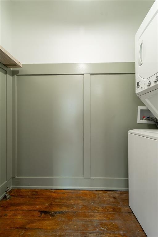 clothes washing area with dark hardwood / wood-style flooring and stacked washer / drying machine