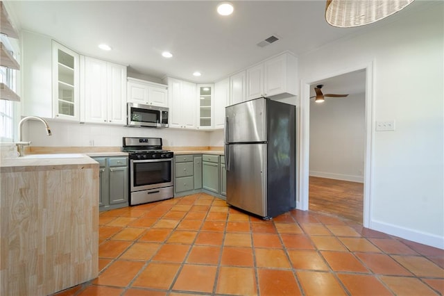 kitchen with white cabinetry, sink, ceiling fan, stainless steel appliances, and light tile patterned floors