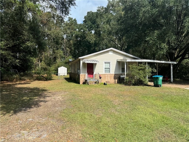 view of front of property featuring a carport, a storage unit, and a front yard