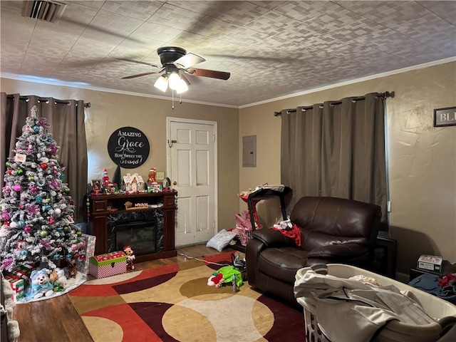 living room featuring ceiling fan, ornamental molding, a fireplace, and electric panel