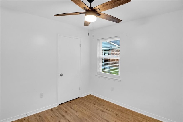spare room with a ceiling fan, light wood finished floors, and baseboards