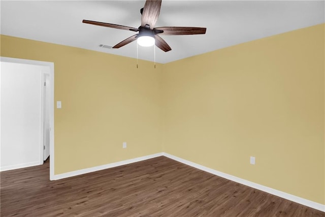 empty room with baseboards, visible vents, a ceiling fan, and dark wood-style floors