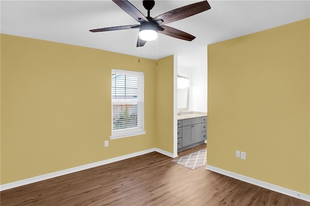 empty room with dark wood-style flooring, ceiling fan, and baseboards