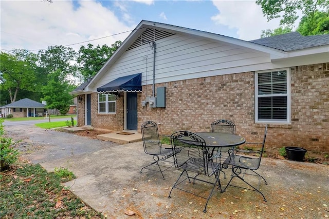 back of house with a patio, outdoor dining area, and brick siding