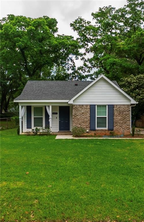 ranch-style home with fence, a front yard, and brick siding