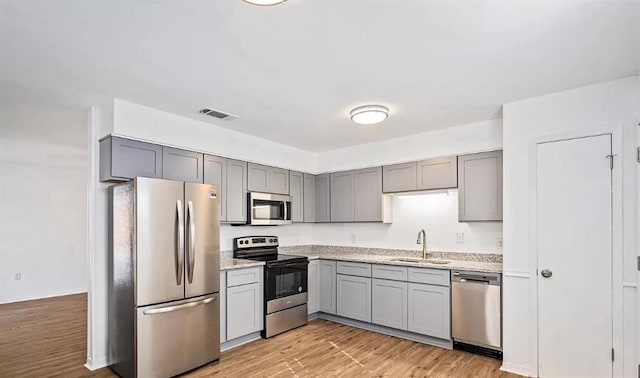 kitchen with gray cabinetry, appliances with stainless steel finishes, and a sink