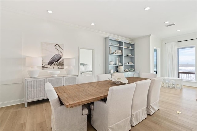 dining area with light wood-type flooring and crown molding