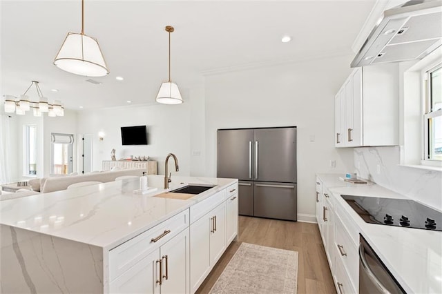 kitchen featuring sink, appliances with stainless steel finishes, a kitchen island with sink, white cabinets, and pendant lighting