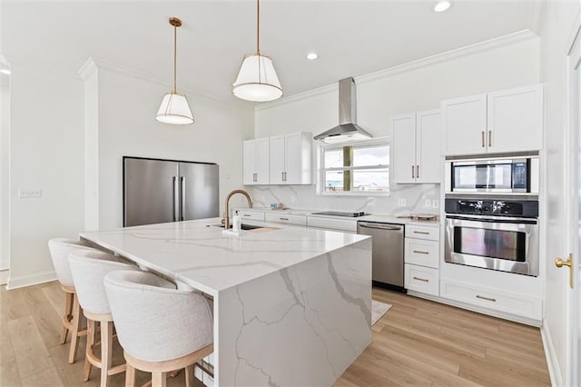 kitchen with stainless steel appliances, a kitchen island with sink, white cabinetry, and range hood