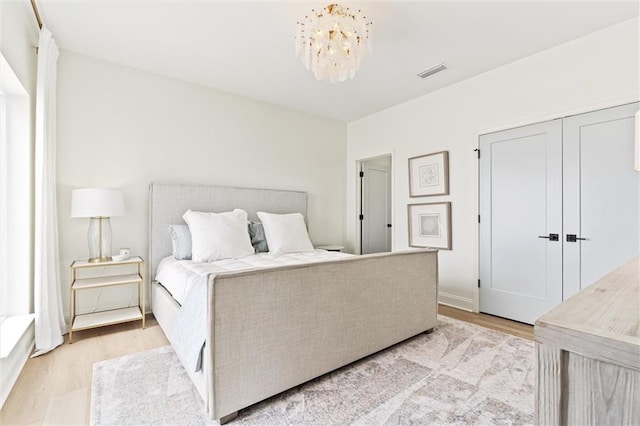 bedroom with a closet, light hardwood / wood-style flooring, and a notable chandelier