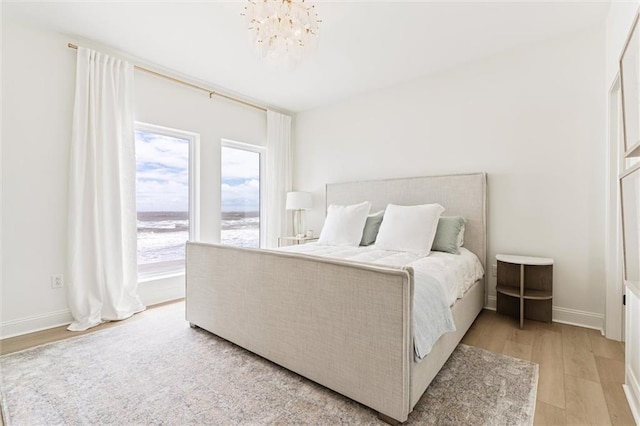 bedroom with light hardwood / wood-style floors and a notable chandelier