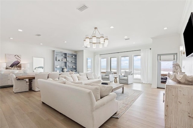 living room with light wood-type flooring, a notable chandelier, and ornamental molding