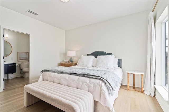 bedroom with light wood-type flooring and ensuite bathroom