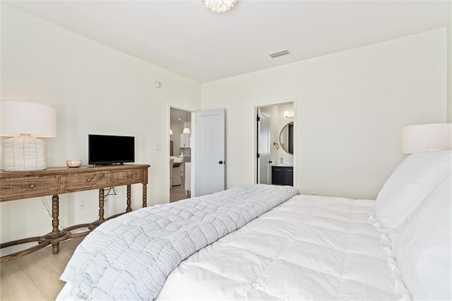 bedroom featuring ensuite bath and wood-type flooring