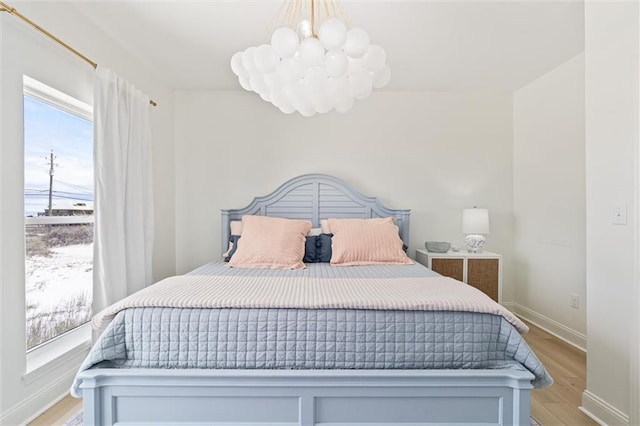 bedroom featuring an inviting chandelier and light hardwood / wood-style flooring