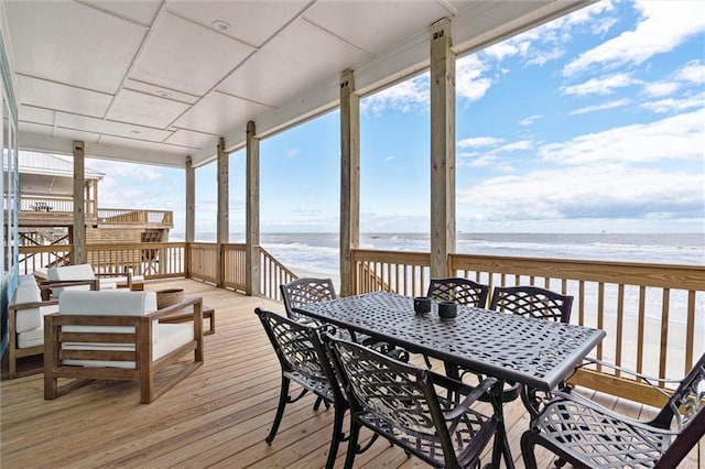 wooden deck featuring a view of the beach and a water view