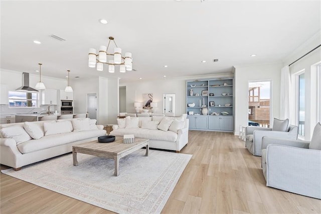 living room featuring light hardwood / wood-style flooring, a notable chandelier, sink, and crown molding