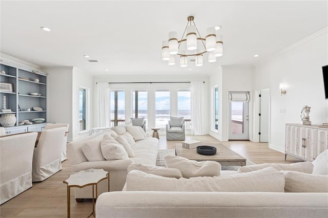 living room with a chandelier, french doors, light hardwood / wood-style floors, and crown molding