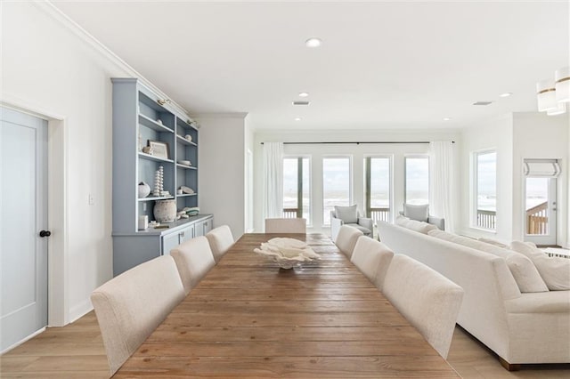 dining space with light hardwood / wood-style floors and crown molding