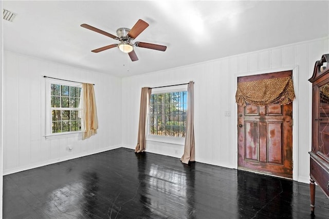 empty room with ceiling fan, a healthy amount of sunlight, and dark hardwood / wood-style floors