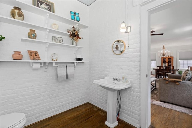 1910 Hunter Ave, Mobile, AL 36606 - bathroom featuring wood finished floors, toilet, brick wall, a chandelier, and a sink