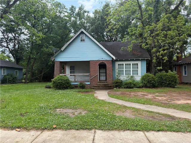 bungalow with covered porch, a front yard, and brick siding