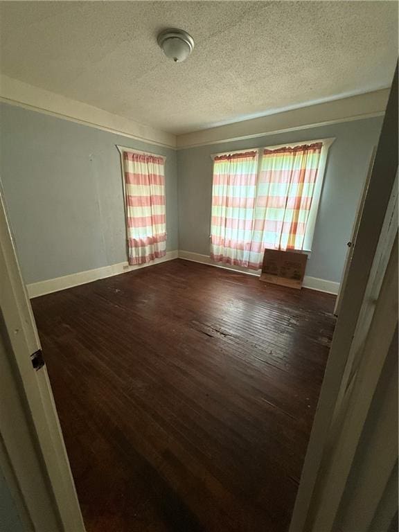 empty room featuring dark wood finished floors, baseboards, and a textured ceiling