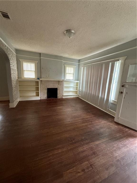 unfurnished living room featuring dark wood-type flooring, plenty of natural light, and a textured ceiling
