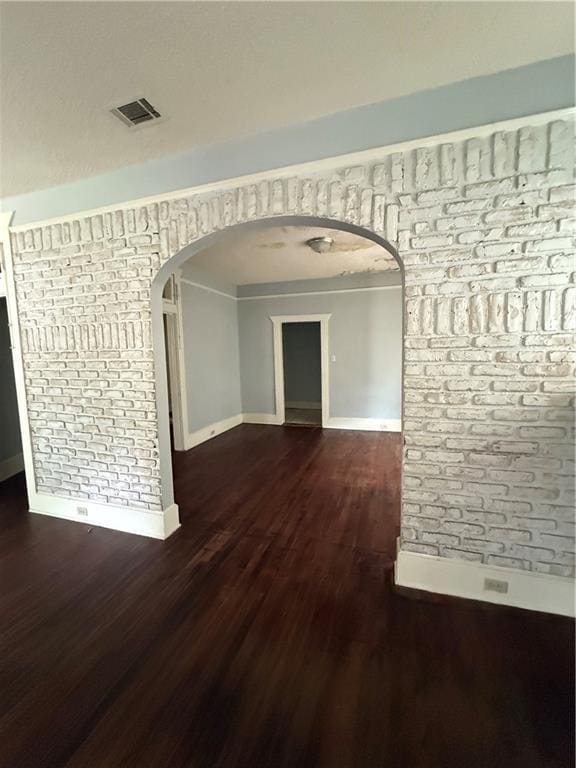 interior space with arched walkways, wood finished floors, visible vents, and baseboards