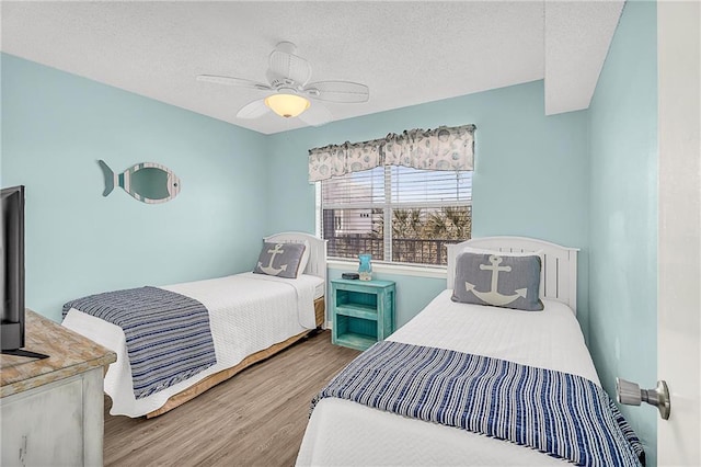 bedroom with a ceiling fan, a textured ceiling, and wood finished floors