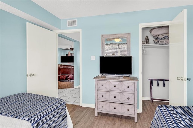 bedroom featuring baseboards, visible vents, a walk in closet, light wood-style floors, and a closet