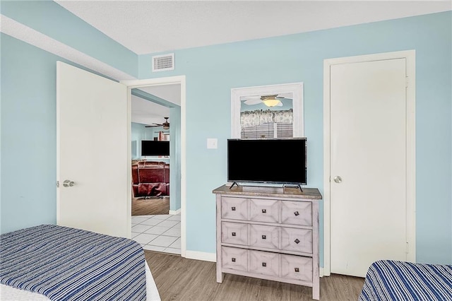 bedroom with light wood-style flooring, visible vents, and baseboards