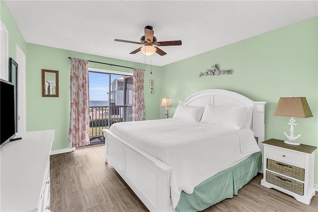 bedroom featuring access to outside, wood finished floors, a ceiling fan, and baseboards