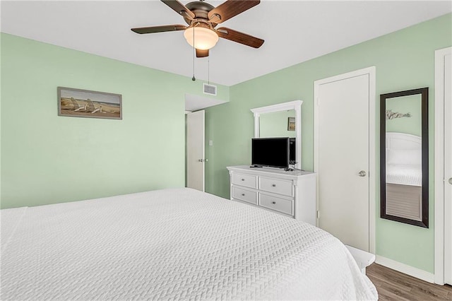 bedroom with a ceiling fan, baseboards, visible vents, and wood finished floors