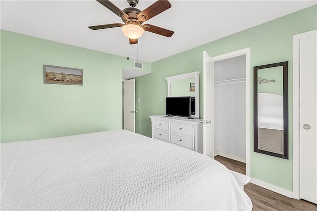 bedroom featuring ceiling fan, wood finished floors, visible vents, baseboards, and a closet