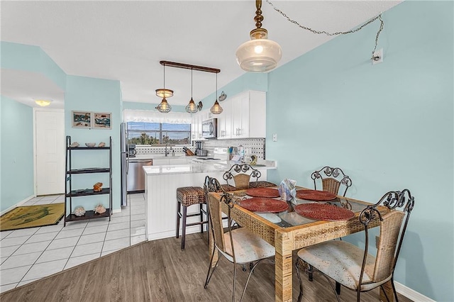 dining space featuring baseboards and light wood finished floors