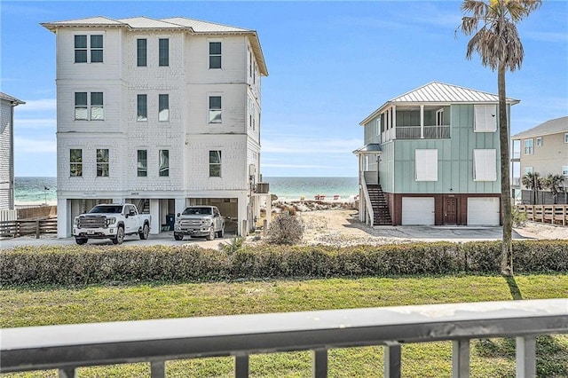 view of building exterior featuring concrete driveway, an attached garage, a water view, stairs, and a carport