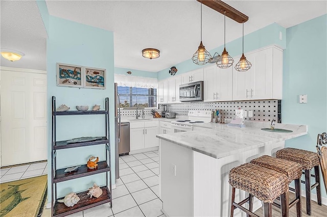 kitchen featuring a peninsula, light tile patterned floors, stainless steel appliances, and a sink