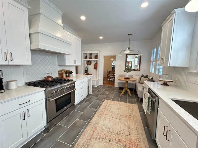 kitchen with decorative light fixtures, premium range hood, white cabinets, and appliances with stainless steel finishes