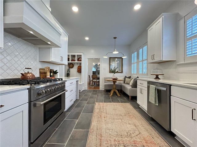 kitchen with appliances with stainless steel finishes, decorative light fixtures, white cabinets, decorative backsplash, and custom exhaust hood