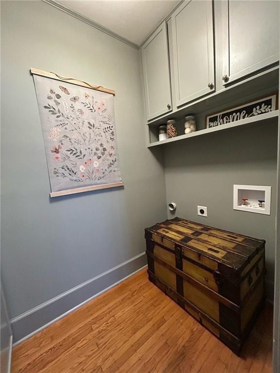 washroom featuring electric dryer hookup, hookup for a washing machine, light hardwood / wood-style floors, and cabinets