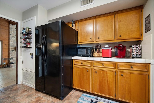 kitchen featuring light tile patterned floors, black appliances, tile countertops, and tasteful backsplash