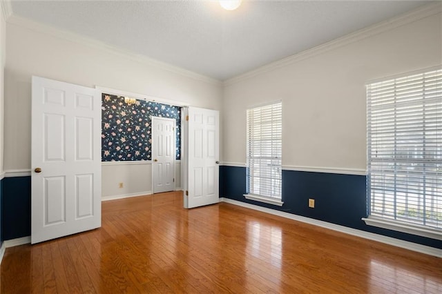 unfurnished room with ornamental molding, wood-type flooring, and a wealth of natural light