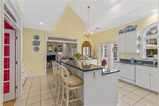 kitchen featuring white dishwasher, a sink, a center island, light tile patterned flooring, and crown molding