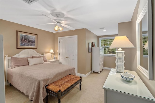 bedroom featuring light colored carpet, baseboards, a ceiling fan, and a closet