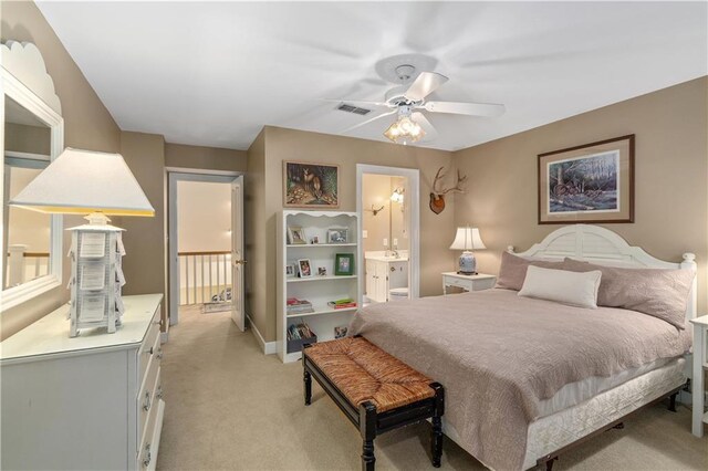 bedroom featuring light carpet, connected bathroom, baseboards, and ceiling fan
