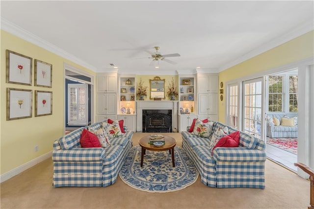 living area featuring ornamental molding, a ceiling fan, a fireplace, baseboards, and built in shelves