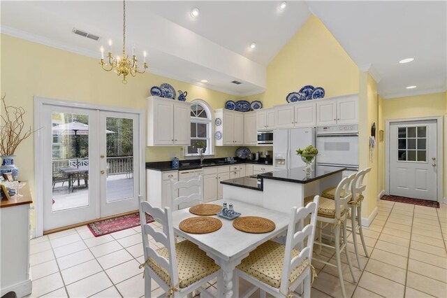 kitchen with white appliances, light tile patterned floors, french doors, a chandelier, and white cabinetry