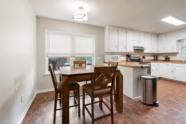 2808 Westmoor Ct, Mobile, AL 36695 - kitchen featuring stainless steel electric range, under cabinet range hood, white microwave, brick patterned floors, and white cabinetry
