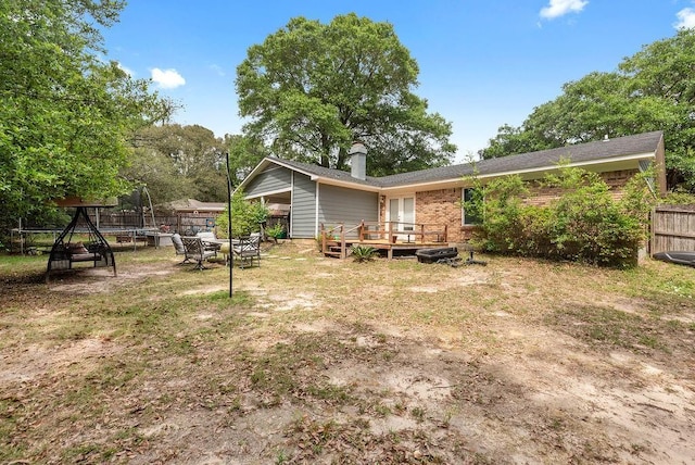 2808 Westmoor Ct, Mobile, AL 36695 - rear view of property featuring a trampoline, a deck, brick siding, and a chimney